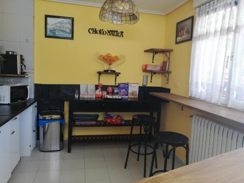 - une cuisine avec un comptoir et quelques tabourets dans l'établissement Txokomaitea, à Urnieta