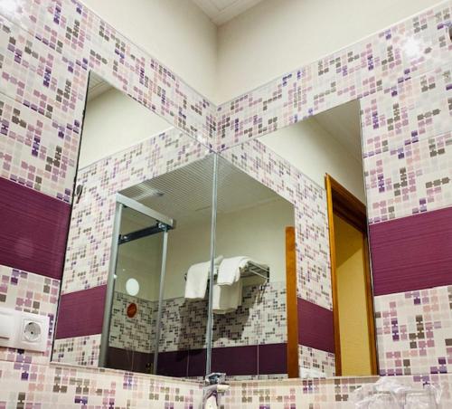 a mirror in a bathroom with a tile wall at Hostal León in Trujillo
