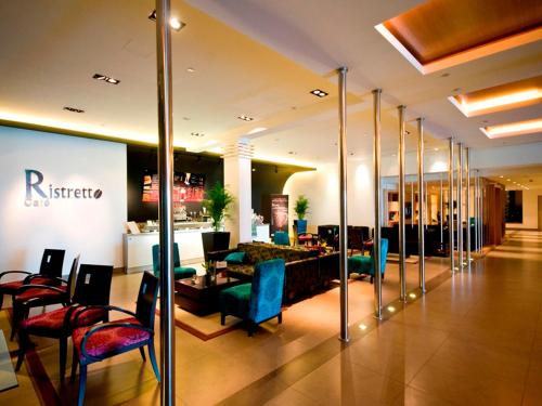 a lobby with chairs and a bar in a building at Amman Airport Hotel in Al Qasţal