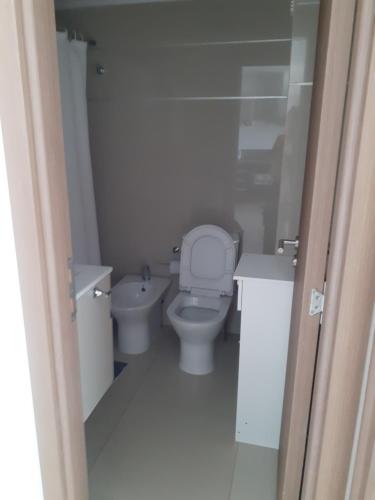 a white bathroom with a toilet and a sink at Solares de Araus 203 in Colonia del Sacramento