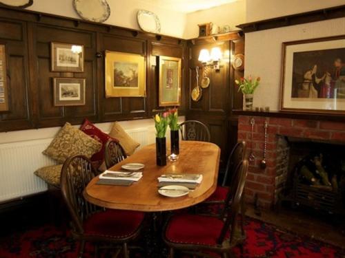 a dining room with a table and chairs and a fireplace at St Quintin Arms in Harpham