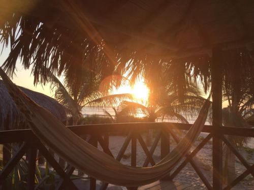 a hammock on a beach with the sunset in the background at Bora Bora Bungalows in Los Órganos