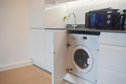 a washing machine with a microwave on top of it at St Albans - Luxury 1 Bedroom Apartment in St. Albans