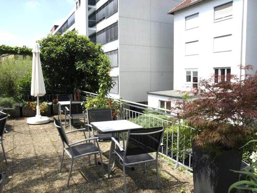 eine Terrasse mit einem Tisch, Stühlen und einem Sonnenschirm in der Unterkunft City Hotel Stuttgart in Stuttgart