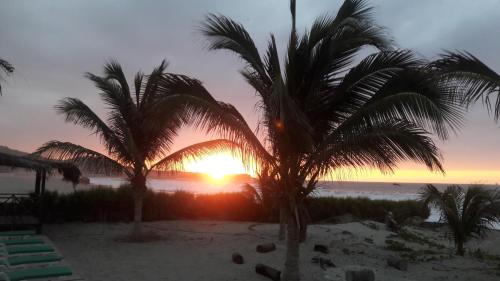 un tramonto sulla spiaggia con palme di Bora Bora Bungalows a Los Órganos