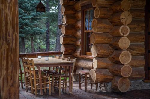 ChamaにあるCorkins Lodgeの丸太小屋の玄関に木製テーブルと椅子