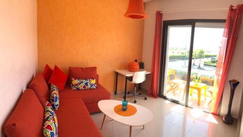 a living room with a red couch and a table at Villa Blanca Beach Pieds-Sur-Mer in Sidi Rahal