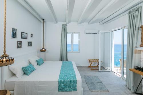 una camera bianca con un grande letto con cuscini blu di Blue Bay Lifestyle - ex Bali Blue Bay a Balíon