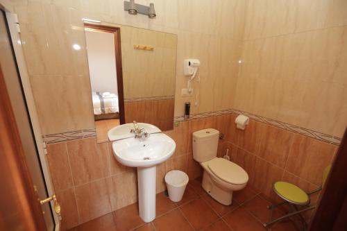 a bathroom with a sink and a toilet and a mirror at Pensión Codesal in O Pedrouzo
