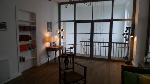 a living room with a large window and a desk at Maison d'hôtes Le 90 in Armentières