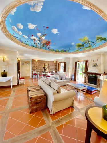 a large living room with a ceiling with a mural at Quinta das Tílias in Santiago do Cacém