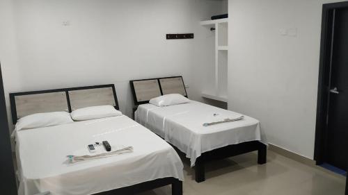 two beds in a room with white sheets at Hotel Jagua Real in La Jagua de Ibirico