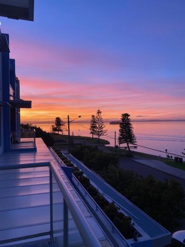 a view of a sunset from a balcony of a building at Lakeside Waterfront Apartment The Entrance in The Entrance