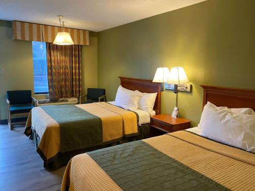 a hotel room with two beds and a chair and a window at Cabarrus Inn in Concord