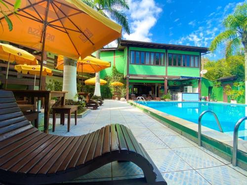 a pool with a bench and umbrellas next to a building at Recanto Verde Praia Hotel Juquehy in Juquei