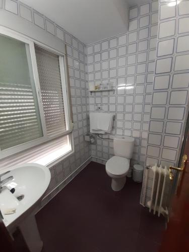 a bathroom with a toilet and a sink and a window at Hotel Andalucía in Cazorla