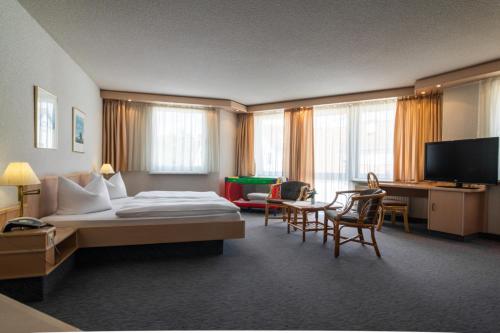 GrötzingenにあるHotel Aichtaler Hofのベッド、デスク、椅子が備わるホテルルームです。