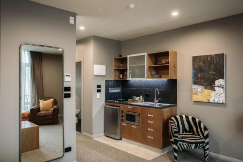 a small kitchen with a sink and a chair at King and Queen Hotel Suites in New Plymouth