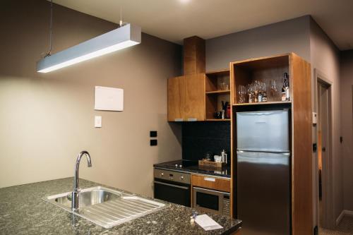 a kitchen with a sink and a refrigerator at King and Queen Hotel Suites in New Plymouth
