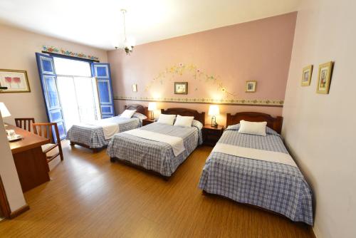 a hotel room with two beds and a table at Hotel Posada del Angel in Cuenca