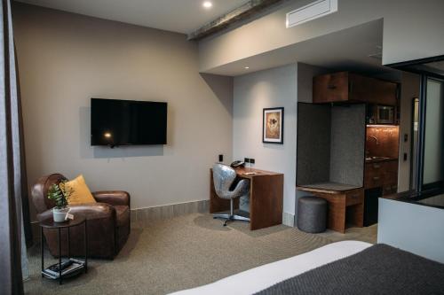 a hotel room with a bed and a desk and a tv at King and Queen Hotel Suites in New Plymouth