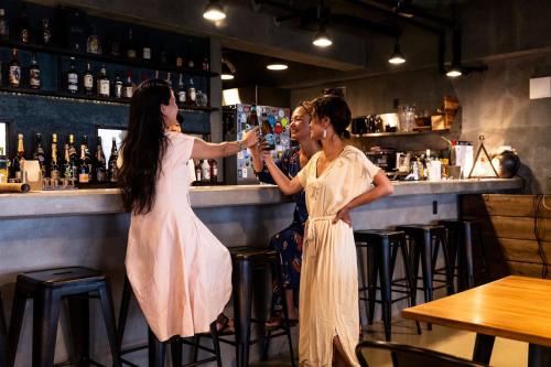 deux femmes debout dans un bar en train de boire dans l'établissement MARINX CLASSIC HARBORVIEW PENSION, à Yaese