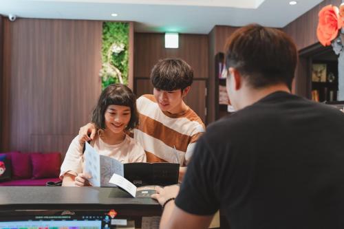 a group of people standing around a table with a laptop at Royal Rose Hotel Xinsheng in Taipei