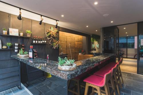 a bar with red chairs and a counter with wine bottles at Royal Rose Hotel Xinsheng in Taipei