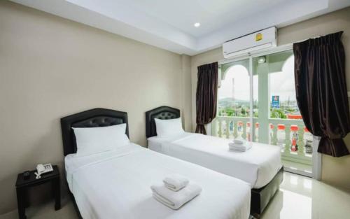 two beds in a room with a window at Tyler Cherngtalay in Ban Pak Lak