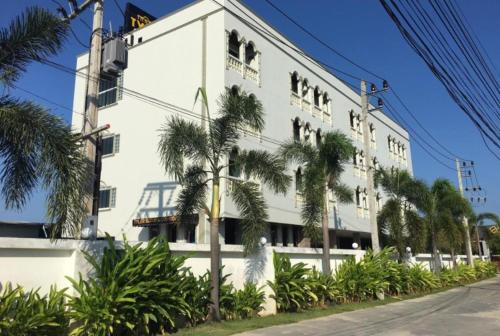 a white building with palm trees in front of it at Tyler Cherngtalay in Ban Pak Lak