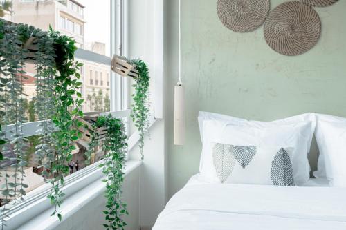 um quarto com uma cama branca e uma janela com hera em Eunoia suite beautiful living in the heart of Athens em Atenas