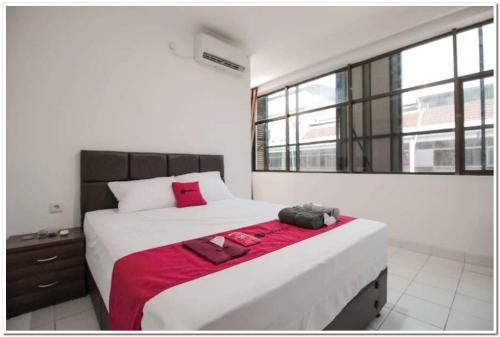 a bedroom with a large bed with a red blanket at RedDoorz @ Ruko ITC Roxy Mas in Jakarta