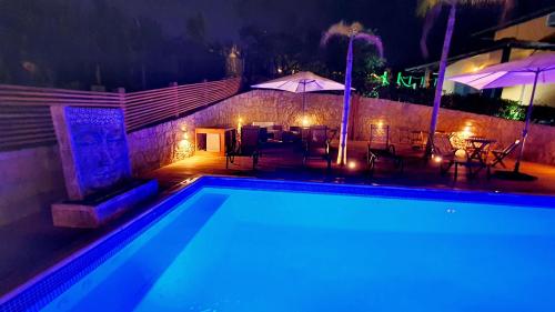 a swimming pool at night with tables and umbrellas at Pousada Paraíso Gaia in Praia do Rosa