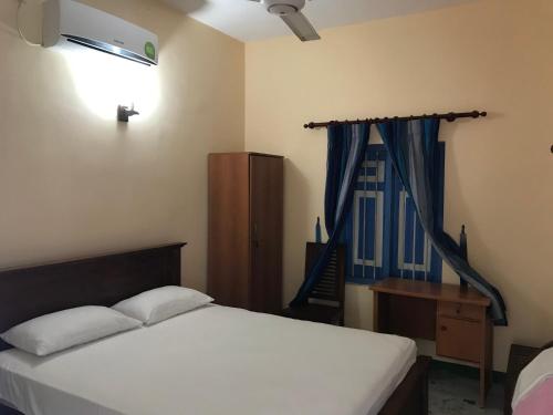 a bedroom with a bed and a desk and a window at Villa Whispering Shells in Kalutara