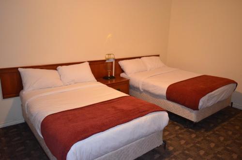 a hotel room with two beds and a lamp at Two Hills Inn in Two Hills