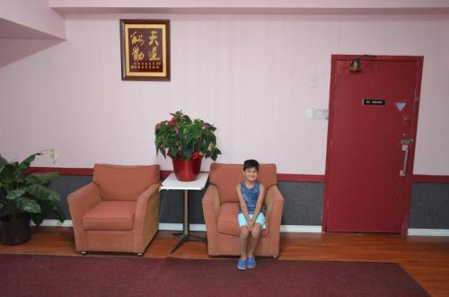 a young boy sitting on a chair in a waiting room at Two Hills Inn in Two Hills