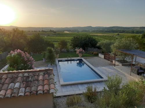 a swimming pool in a garden with a view of a vineyard at L'ARCHIMBAUDE in Pertuis