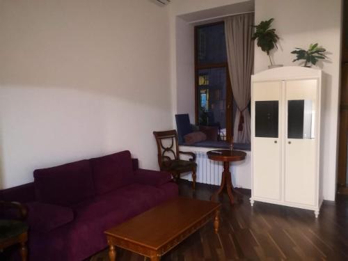 a living room with a purple couch and a table at Затишні апартаменти, Дерибасівська in Odesa