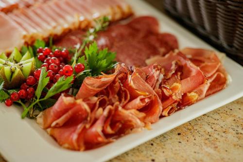 a plate of food with meat and fruit on a table at Hotel Garni Toscanina - Adults Only in Bad Radkersburg
