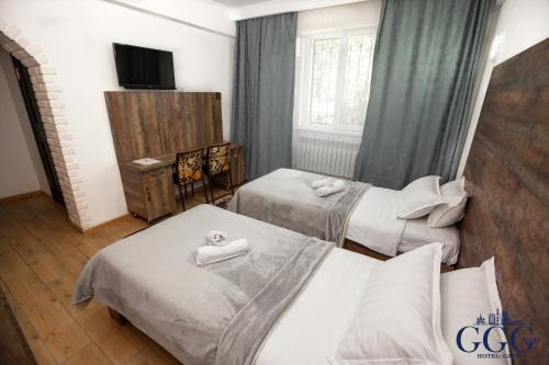 a hotel room with two beds and a television at GG Group Hotel in Almaty