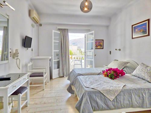 a bedroom with a bed and a desk with flowers on it at Avraki in Kamari