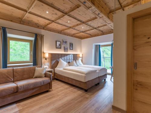 1 dormitorio con 1 cama y 1 sofá en Alpen Glück Hotel Unterm Rain garni en Kirchberg in Tirol