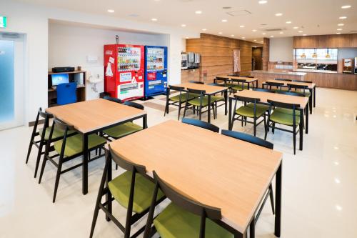 a cafeteria with tables and chairs and a kitchen at Super Hotel Fujinomiya in Fujinomiya
