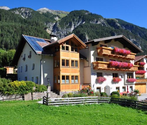 a house with a mountain in the background at Pension Roman in Pettneu am Arlberg