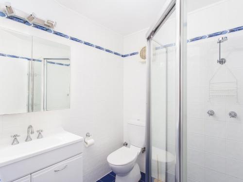 a white bathroom with a toilet and a shower at Forster Holiday Lodge 09 in Forster