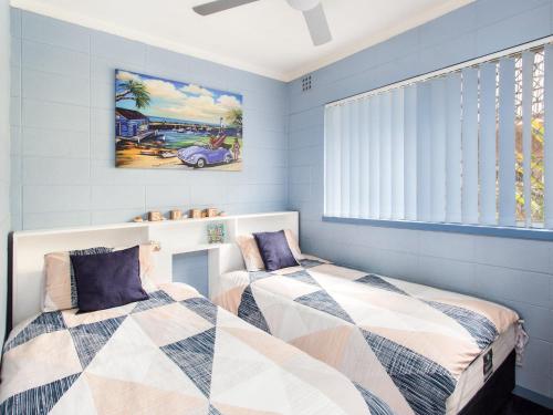 Duas camas num quarto com paredes azuis em Forster Holiday Lodge 09 em Forster