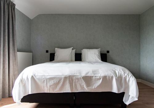 Gîte XXV House - 4 personnes في Héron: سرير بشرشف ووسائد بيضاء في غرفة النوم