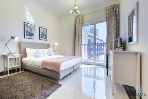 a bedroom with a bed and a balcony at Eclectic 1BR in Pantheon Boulevard by Deluxe Holiday Homes in Dubai