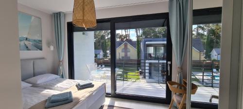 a bedroom with a bed and a view of a balcony at BOHO MARE Apartament Pobierowo in Pobierowo