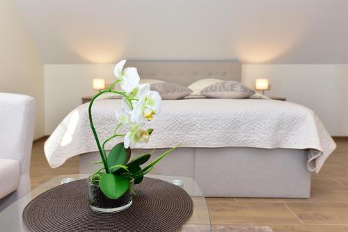 a vase with white flowers on a table in a bedroom at Panorama in Trakai